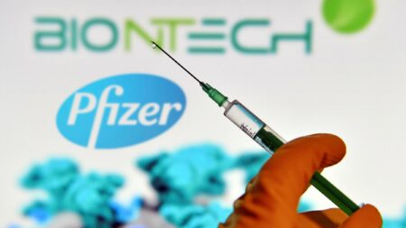 strzykawka ze szczepionką, w tle logo Pfizer