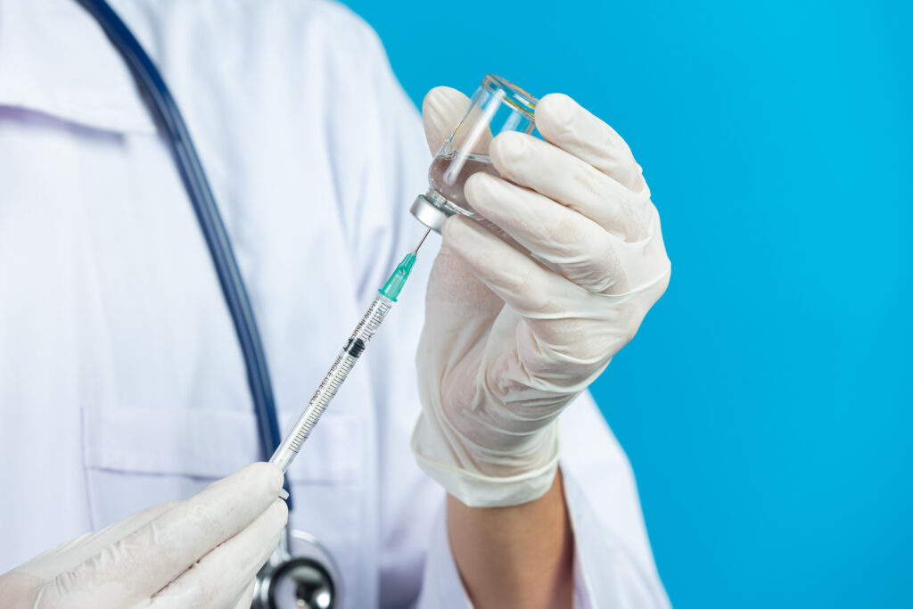 lekarz pobierający dawkę szczepionki do strzykawki