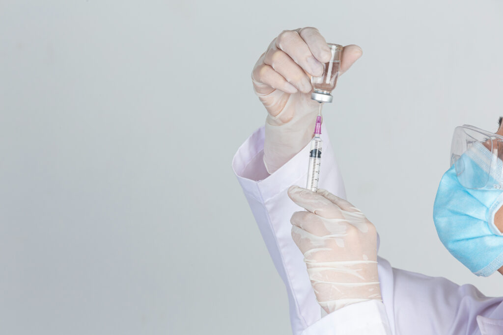 lekarz pobierający dawkę szczepionki do strzykawki