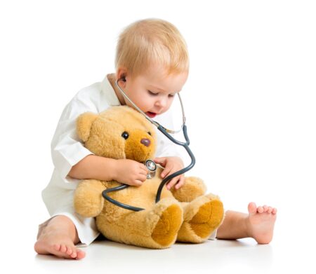 obrazek przedstawia dziecko przebrane za lekarza i badające misia