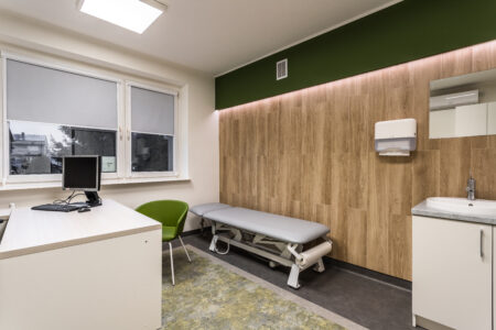 Zdjęcie przedstawia gabinet lekarski nr 1. Po lewej stronie (przy ścianie) jest leżanka regulowana elektrycznie. Przed leżanką jest krzesło dla pacjentów.